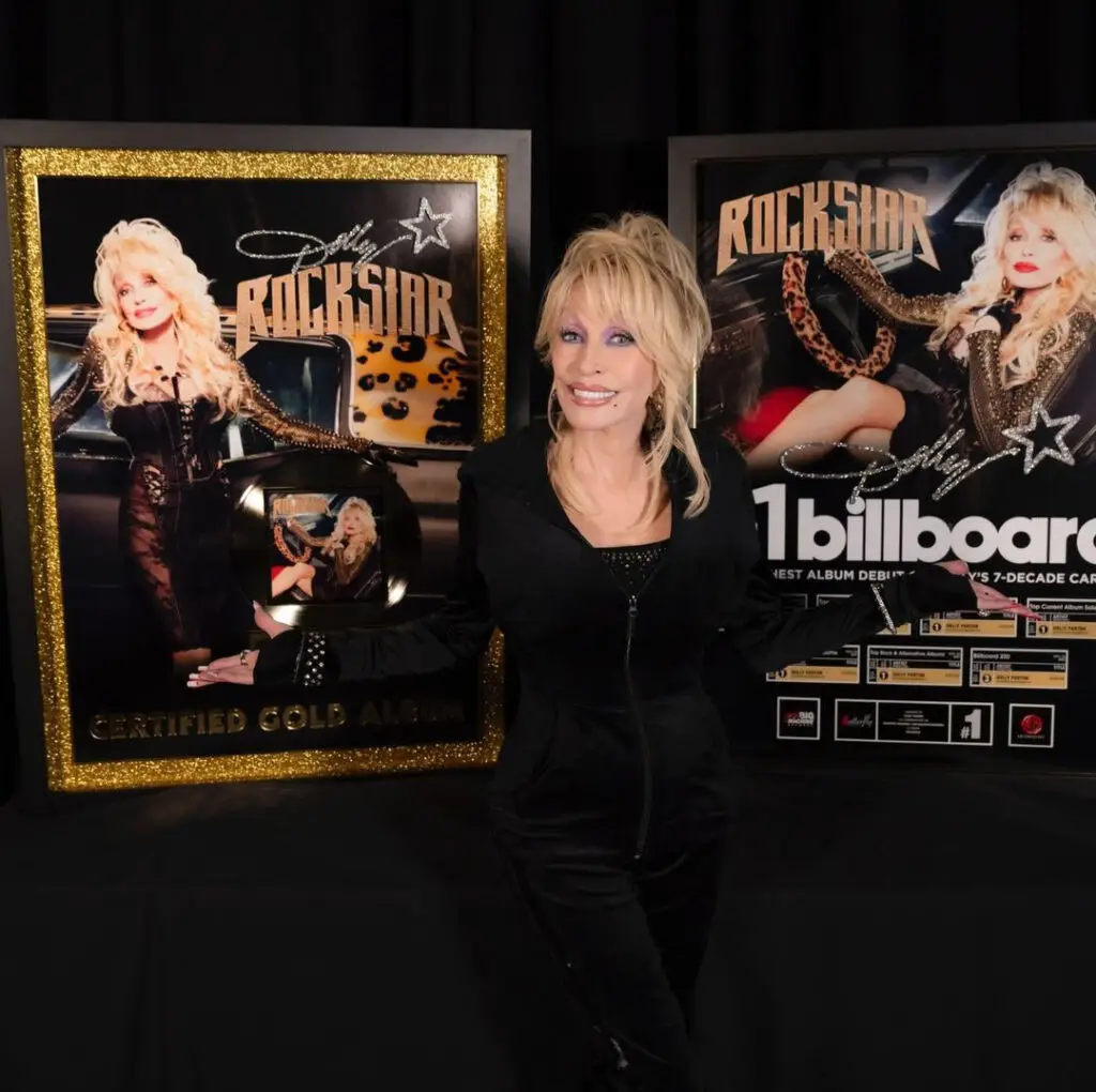 Dolly Parton standing in front of two custom billboard music awards